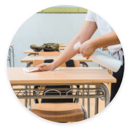 person wiping down desk in school