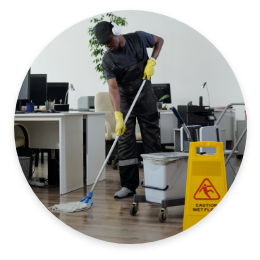 person with mop bucket and mop with wet floor sign working on a floor