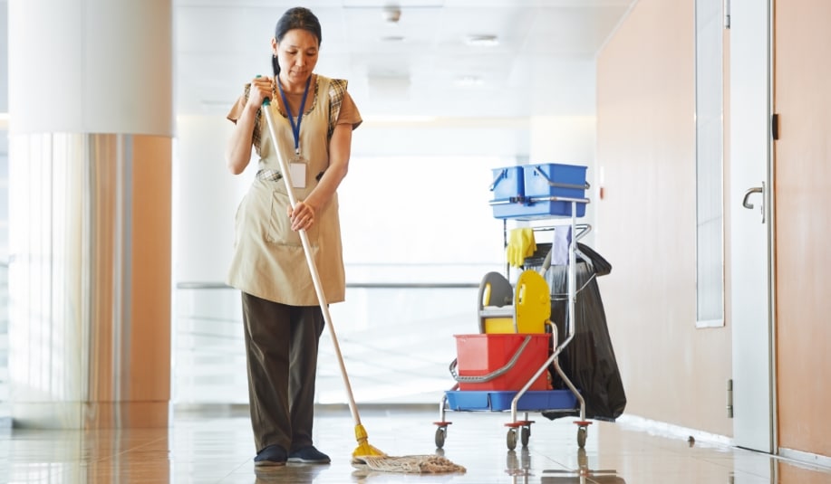 janitorial staff using a mop on an office floor