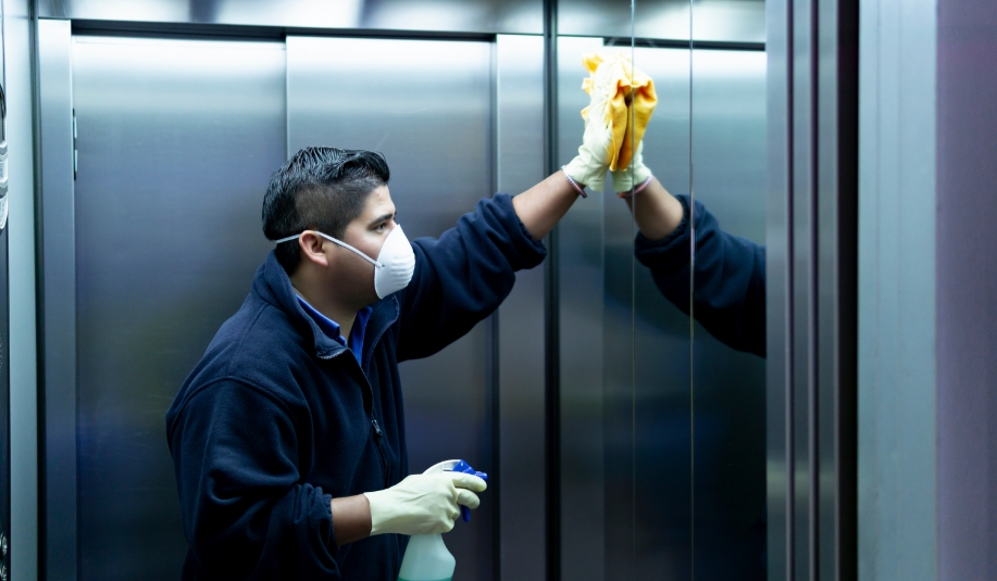 man in N95 mask cleaning elevator walls